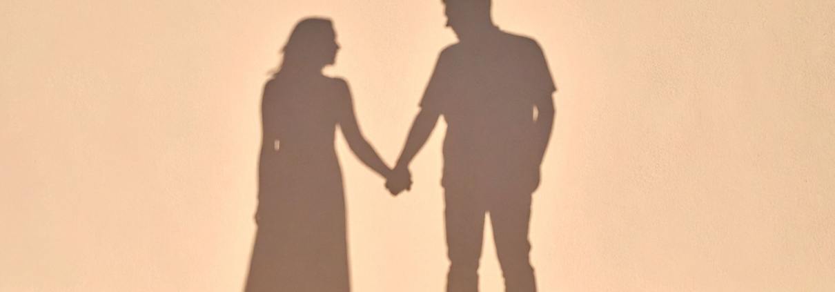 Shadows of a couple holding hands in warm sunlight, on rebuilding trust after an affair